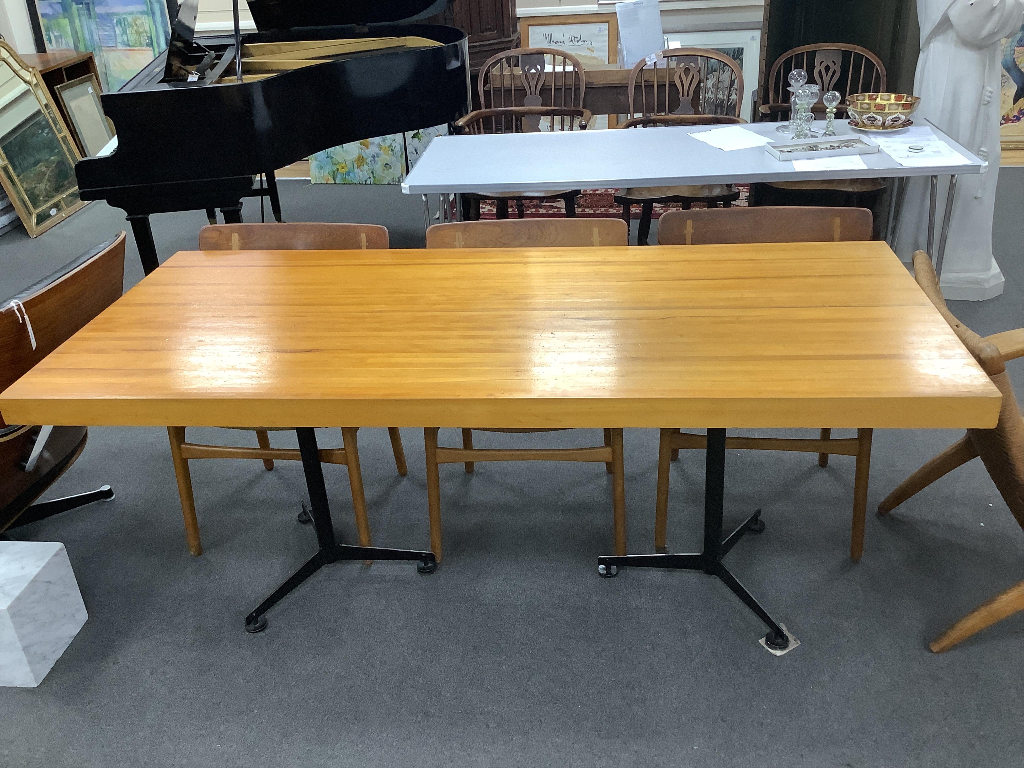 In the manner of Charlotte Perriand, a mid century rectangular maple dining table on twin three prong cast metal end standards, width 179cm, depth 81cm, height 71cm. Condition - fair to good